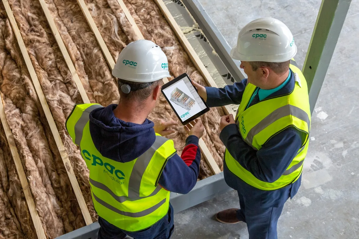 Équipe chantier consultant un plan de travaux sur tablette